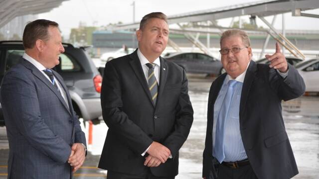 ​SUNNY SIDE: Sydney Markets CEO Brad Latham inspecting the newly opened solar car park facility with NSW planning minister, Anthony Roberts, and Sydney Markets chairman, John Pearson. The facility can handle 640kW and will save 936 tonnes of carbon each year.