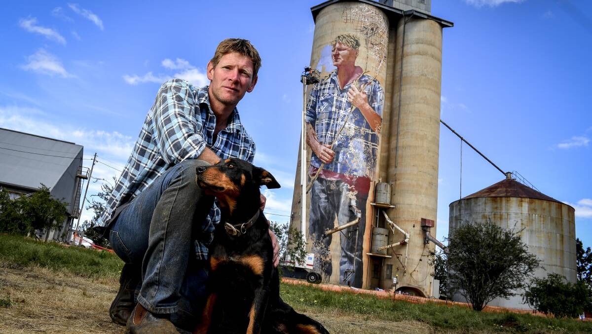 Local sheep and wheat farmer Nick Hulland, who is depicted on the disused silos at Patchewollock, in the Mallee, with his dog Wally. Photo: Eddie Jim