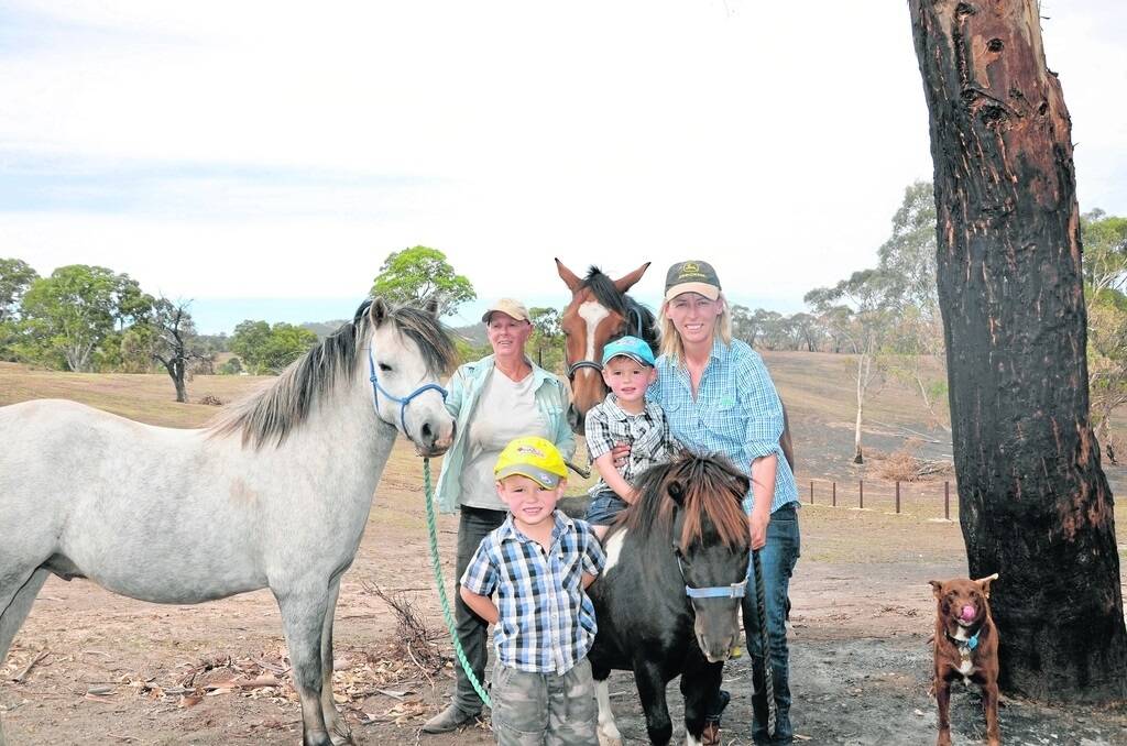  Banyula Park horse agistment owner Jen Tiver (right) with one of her agistees Robbie Lowe, who helped defend the property with Jen’s husband Heath, during the Sampson Flat bushfire. They are with Jen’s sons Jack and Angus and horses Khan, Sam and Patches and dog Dusty by a burnt out section adjacent shedding on the property.