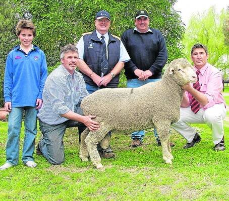 Tyke and Kym Staude, KD Dohne stud, Bordertown, were all smiles in selling their $4000 top price Dohne ram, to John Davidson, Carinya, Mininera, Victoria and his agent Australian Wool Network Portland's Michael Crooks. Pictured holding the ram is Elders auctioneer Laryn Gogel.