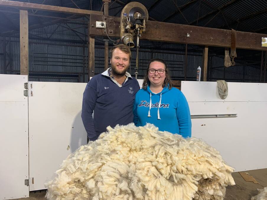 DUAL INCOME: Mitchell Baker and partner Micaela Lock inspect some of the family's annual woolclip.