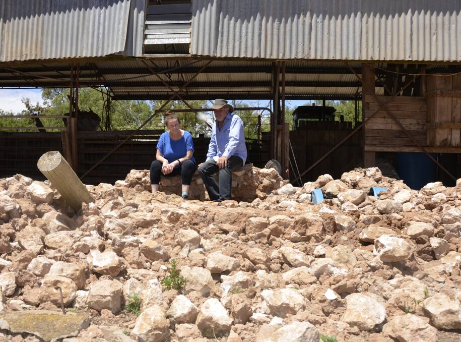 DESTRUCTION: Bernadette and Anthony Smith in the rubble of the 120-year-old shearing shed wall that collapsed during the flood in October.