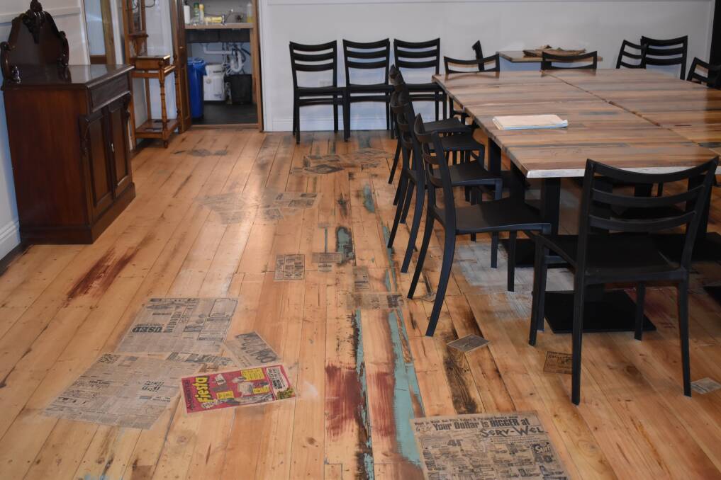The papers from under the old lino floor have been reused with local content lacquered to the wooden floor. Picture by Kiara Stacey